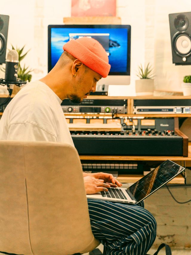 Music producer setup with laptop and MIDI keyboard in home studio.